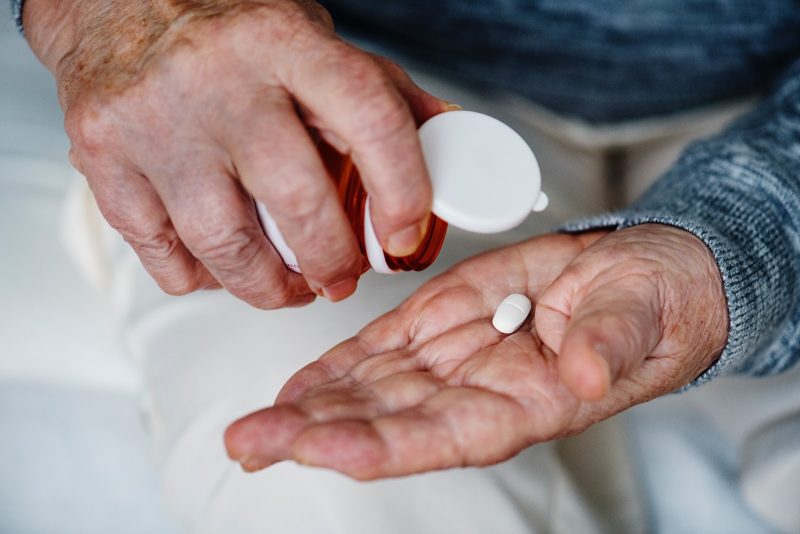 Man dispensing pill from container into hand