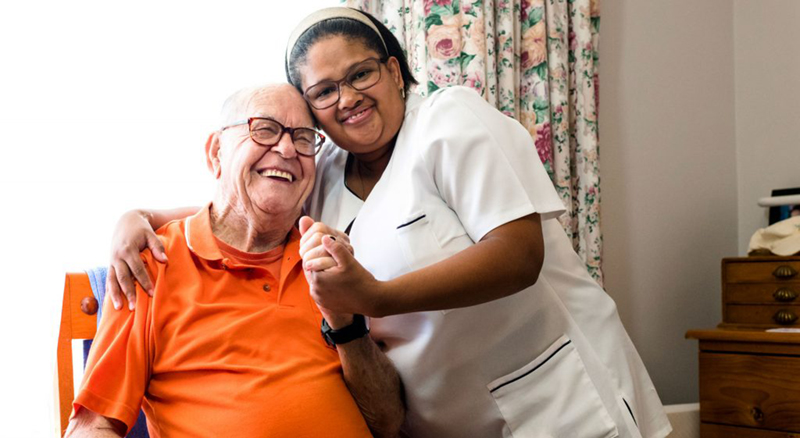 Caregiver hugging senior while both are smiling