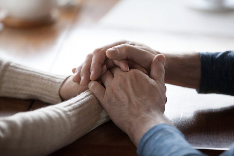 Two people hold hands while seated at desk at SmithLife Homecare in Washington DC