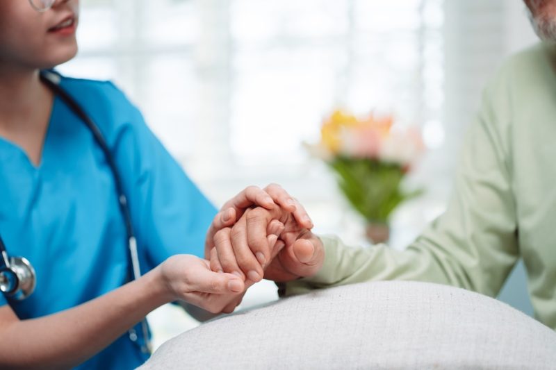 Nurse holding hospice client's hand in Rockville, MD