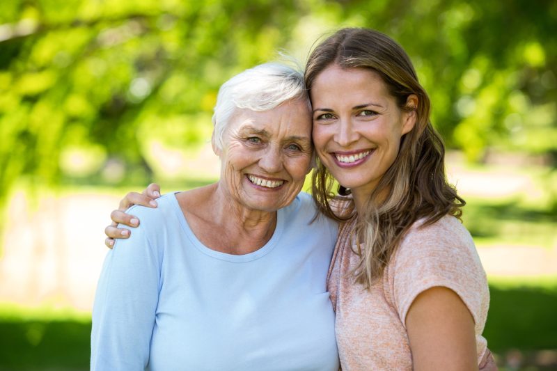 A daughter and her senior mother leaning into each other