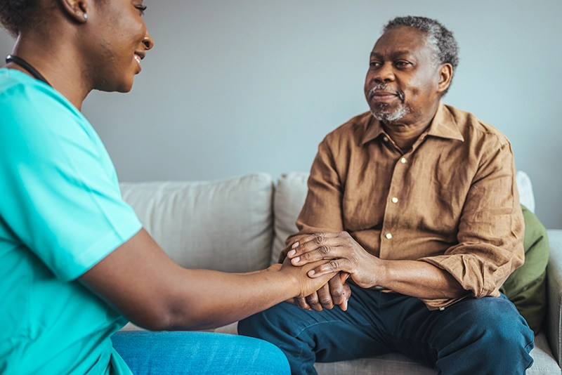 Caregiver sitting and holding a senior's hand while providing companion care